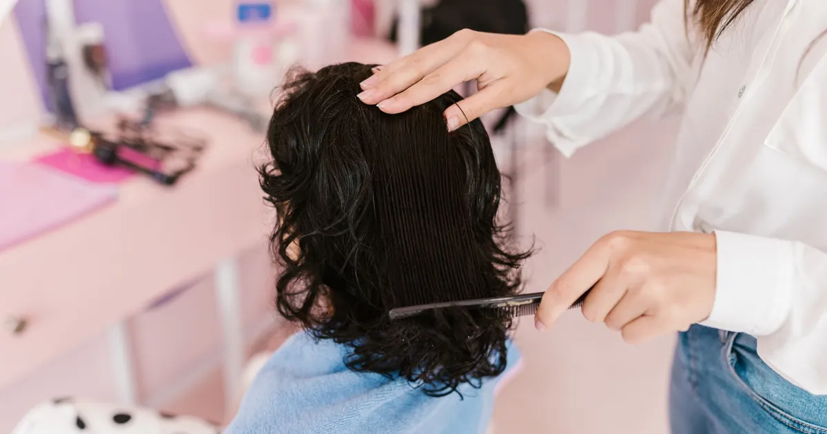 Gros plan sur une femme recevant un soin coiffant dans un salon contemporain, geste précis
