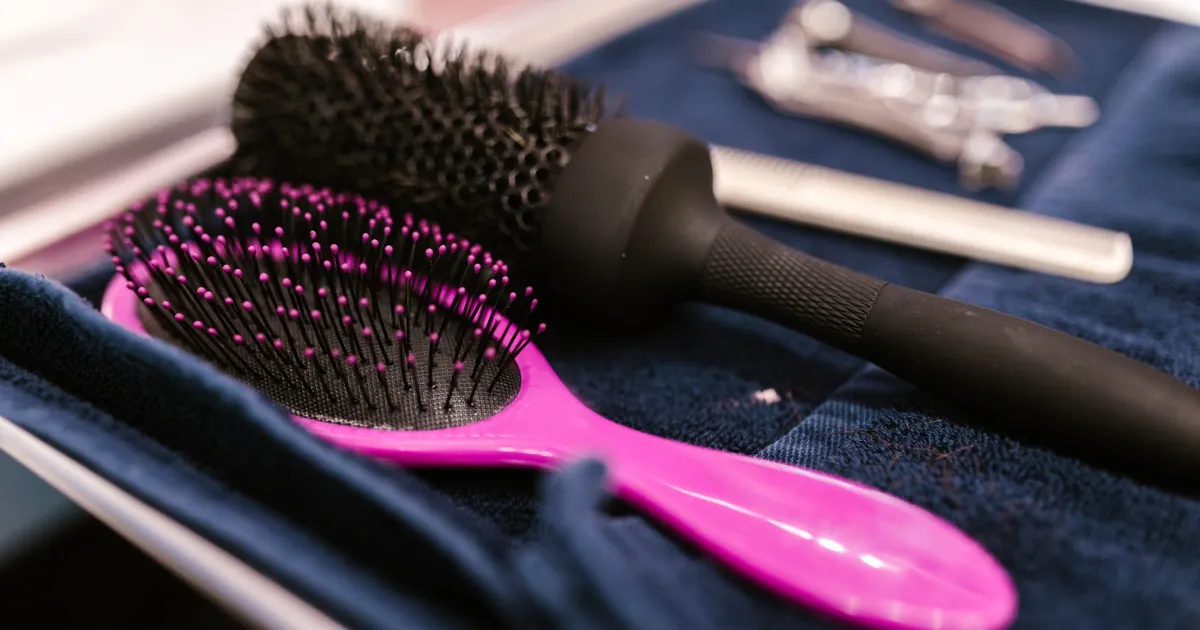 Brosses à cheveux roses et noires posées sur une serviette au salon