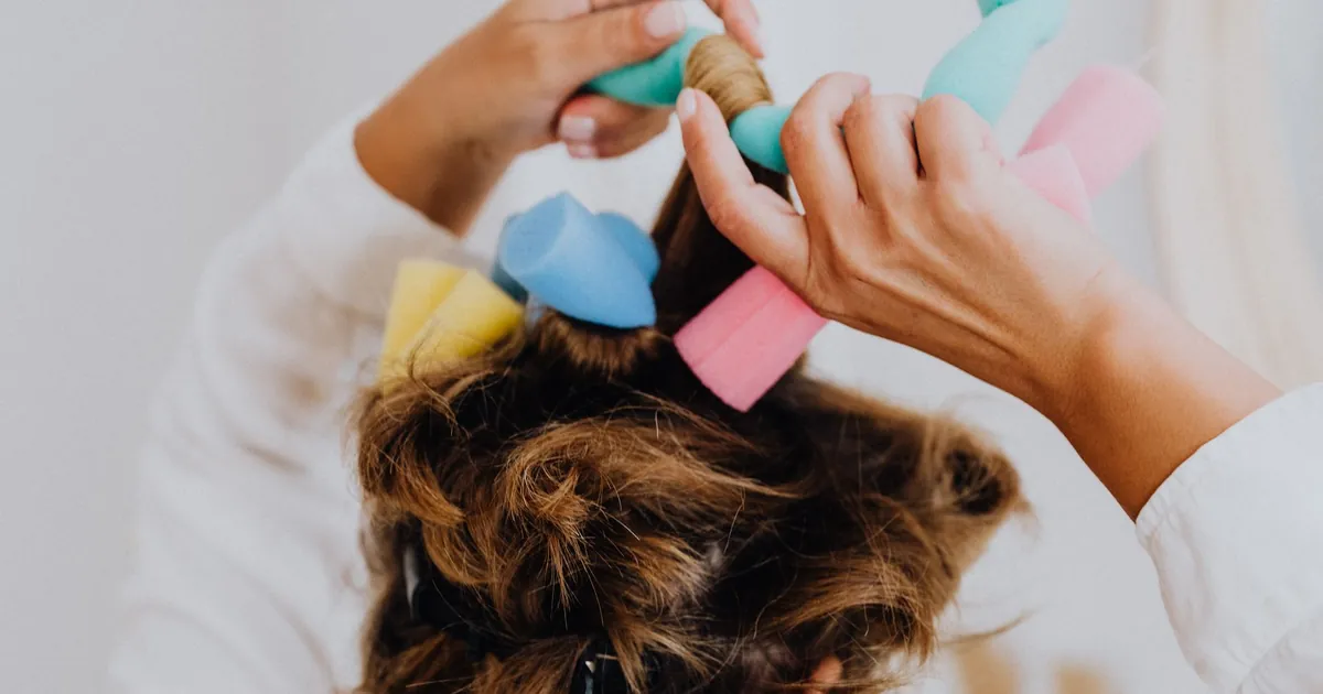 Femme coiffant ses cheveux avec des bigoudis en mousse