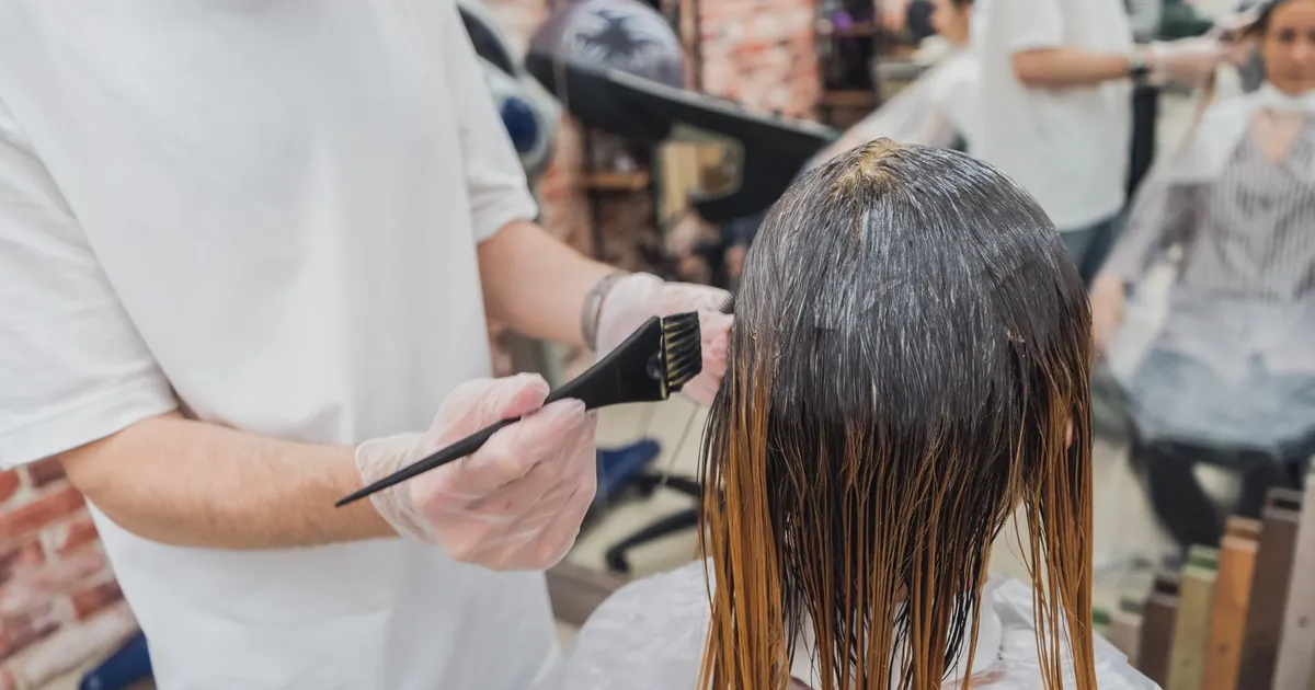 Coloration en salon : une coiffeuse applique la couleur sur les cheveux d'une cliente.