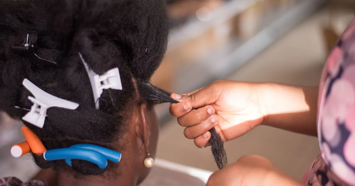 Coiffeur coiffant les cheveux d'une femme avec des pinces en salon, gros plan sur les mains