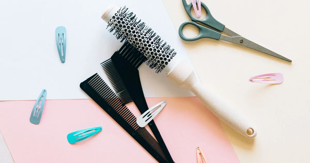 Outils de coiffure à plat sur fond pastel : peignes, brosses et pinces