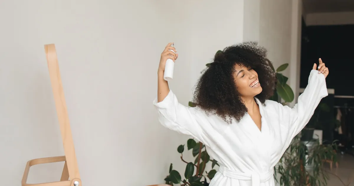 Femme aux cheveux bouclés en peignoir profitant de sa routine matinale.