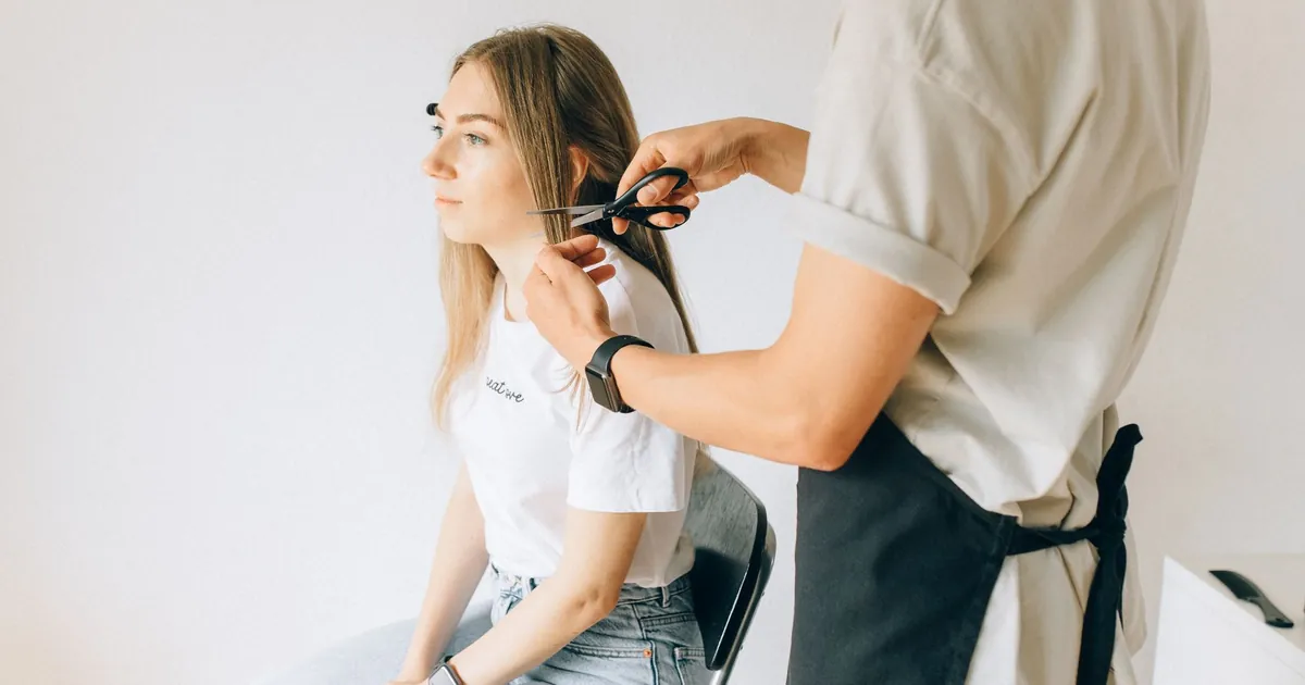 Une femme se fait couper les cheveux par un coiffeur dans un salon moderne.
