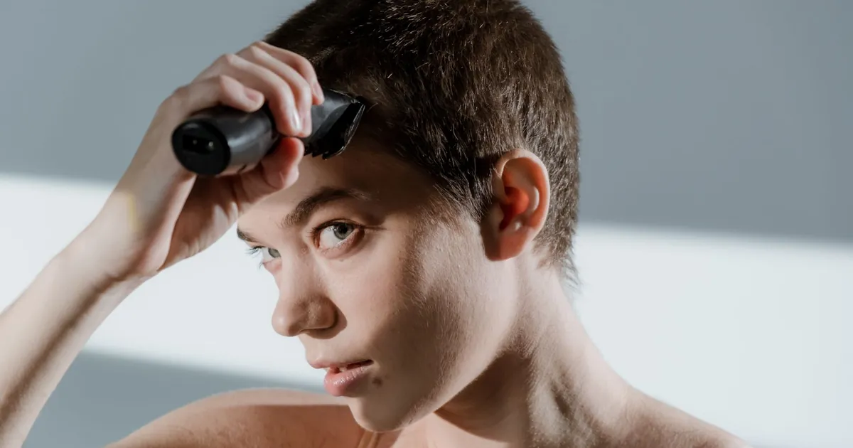 Gros plan sur une femme qui coupe ses cheveux courts à la tondeuse.