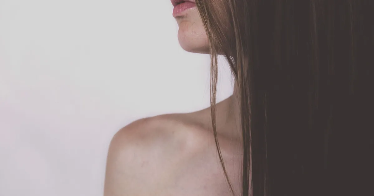 Portrait serré sur l'épaule élégante d'une femme et ses longs cheveux soyeux.