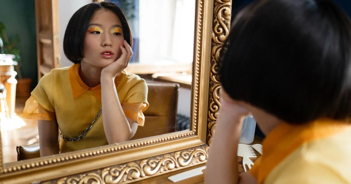 Femme pensive devant le miroir d'un salon entourée d'outils de coiffure