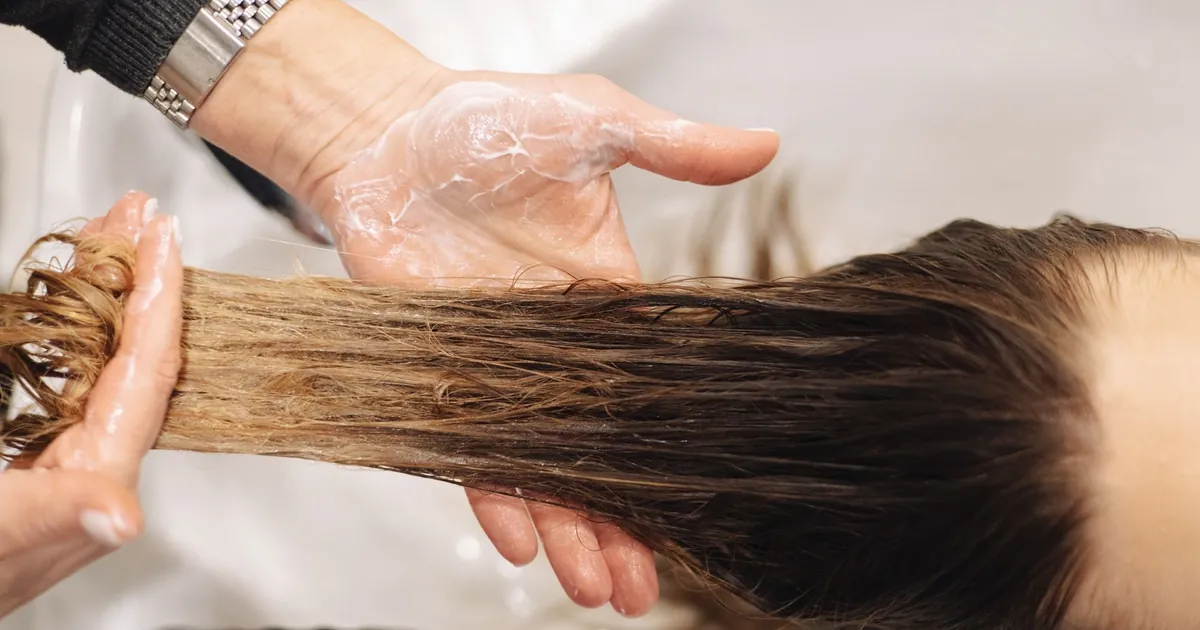 Lavage de cheveux professionnel en salon, geste des mains en gros plan.