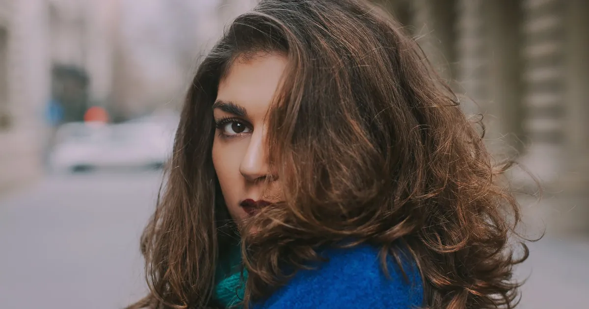 Femme en manteau bleu aux cheveux volumineux en extérieur