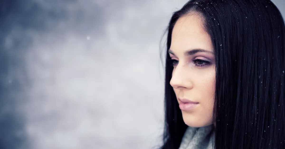 Femme aux longs cheveux noirs sous la neige, flocons posés sur ses cheveux