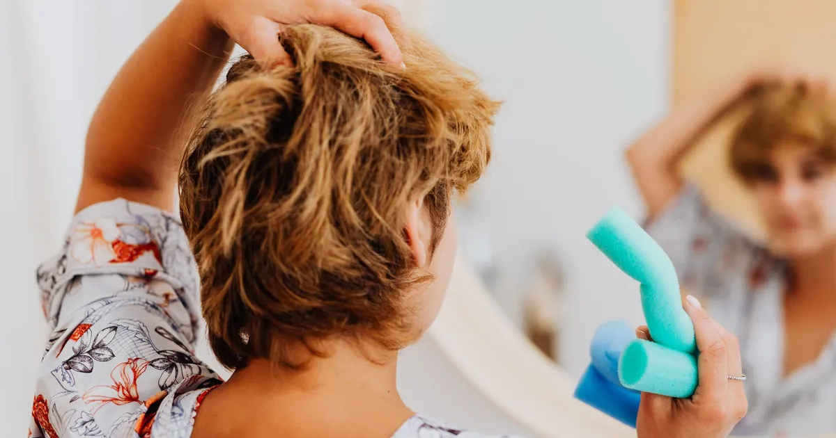 Femme posant des bigoudis devant le miroir de sa salle de bain