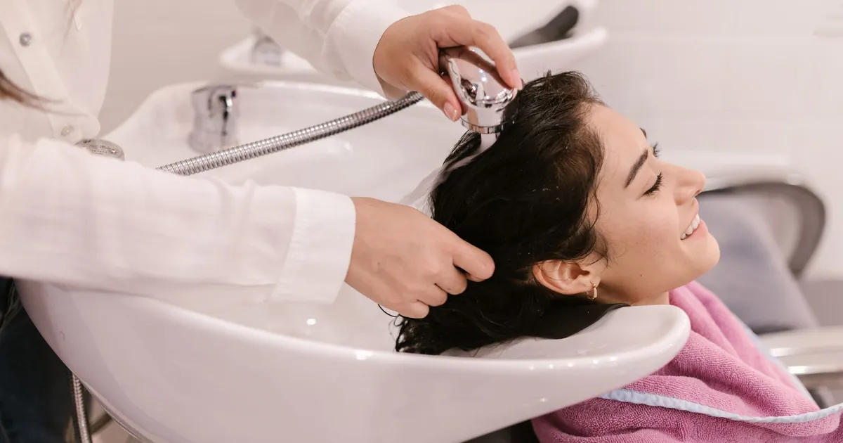 Jeune femme détendue pendant un lavage de cheveux dans un salon moderne.