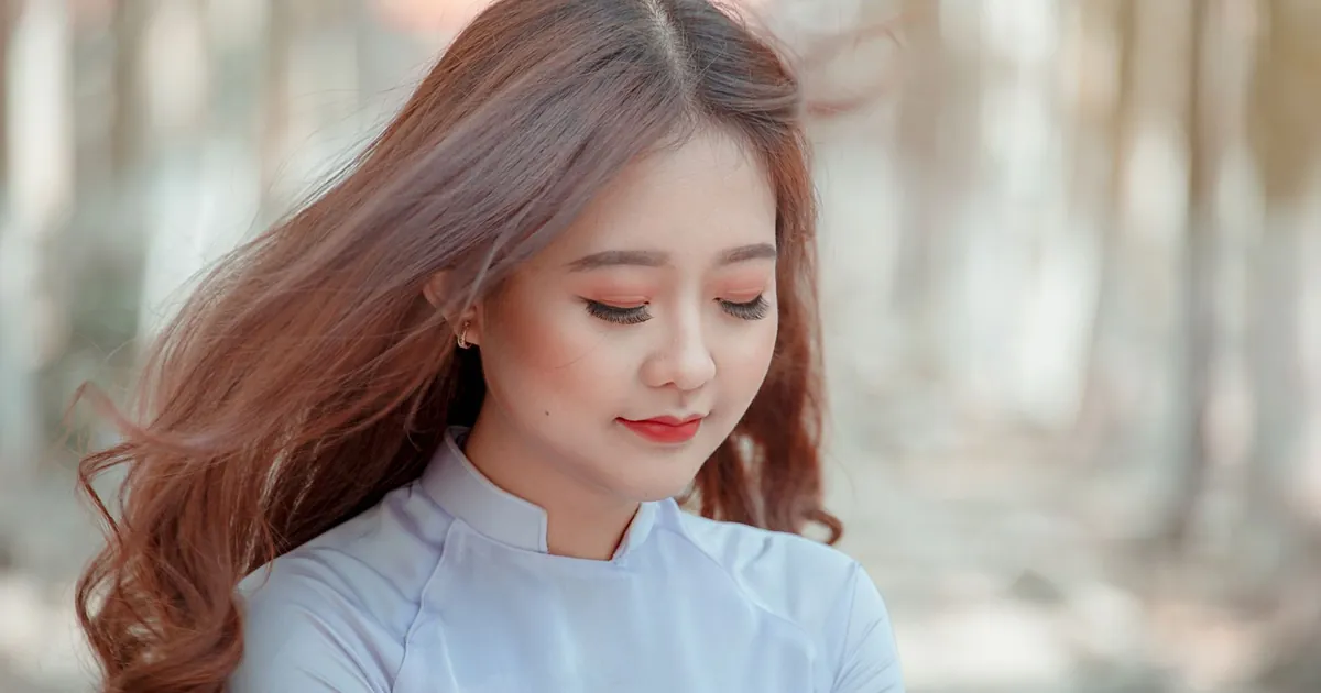 Jeune femme aux cheveux fluides profitant d'un moment paisible en extérieur.