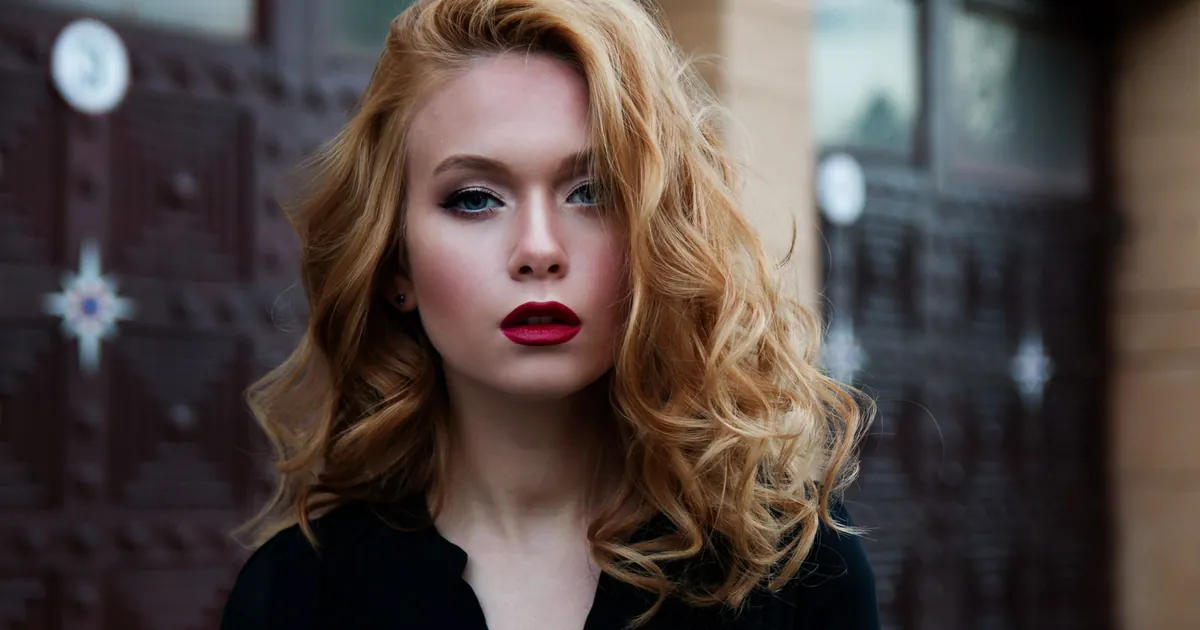 Portrait élégant d'une femme en haut noir, lèvres rouges et cheveux blonds fluides