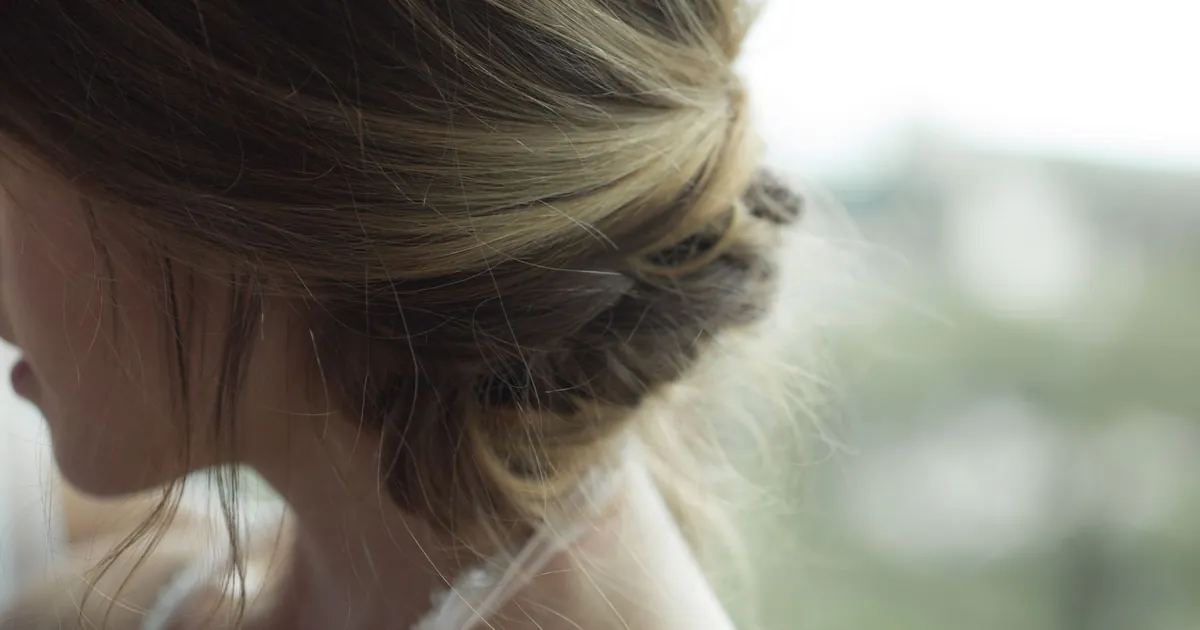 Gros plan sur une élégante coiffure blonde relevée d'une femme à l'intérieur.
