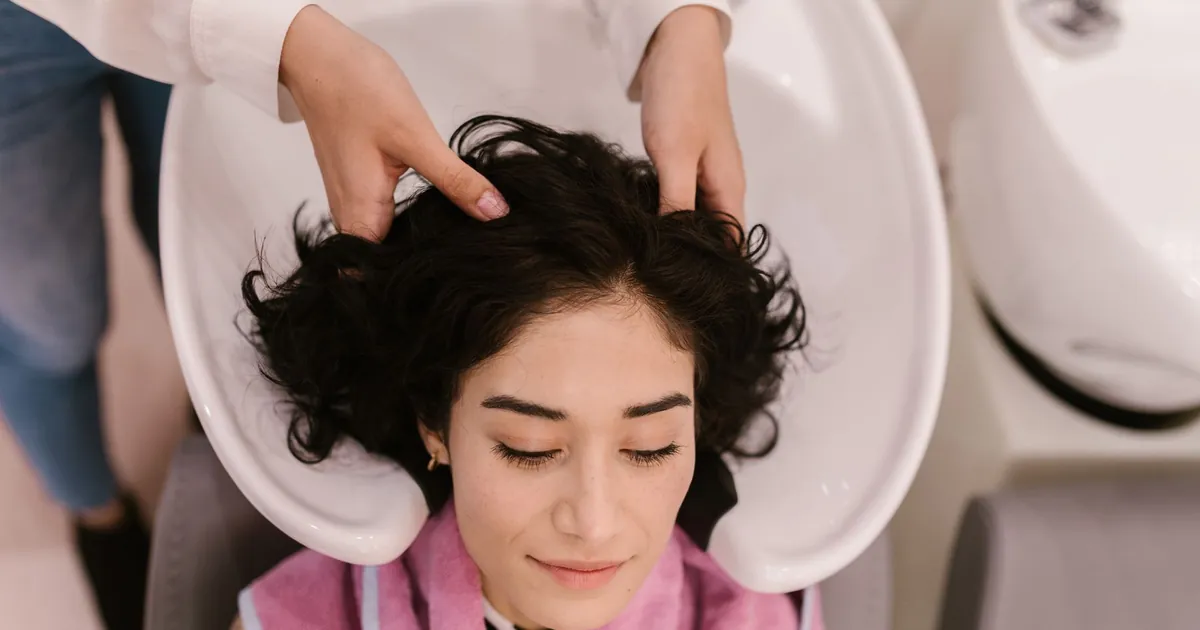 Une femme sereine se fait laver et masser les cheveux dans un salon contemporain.