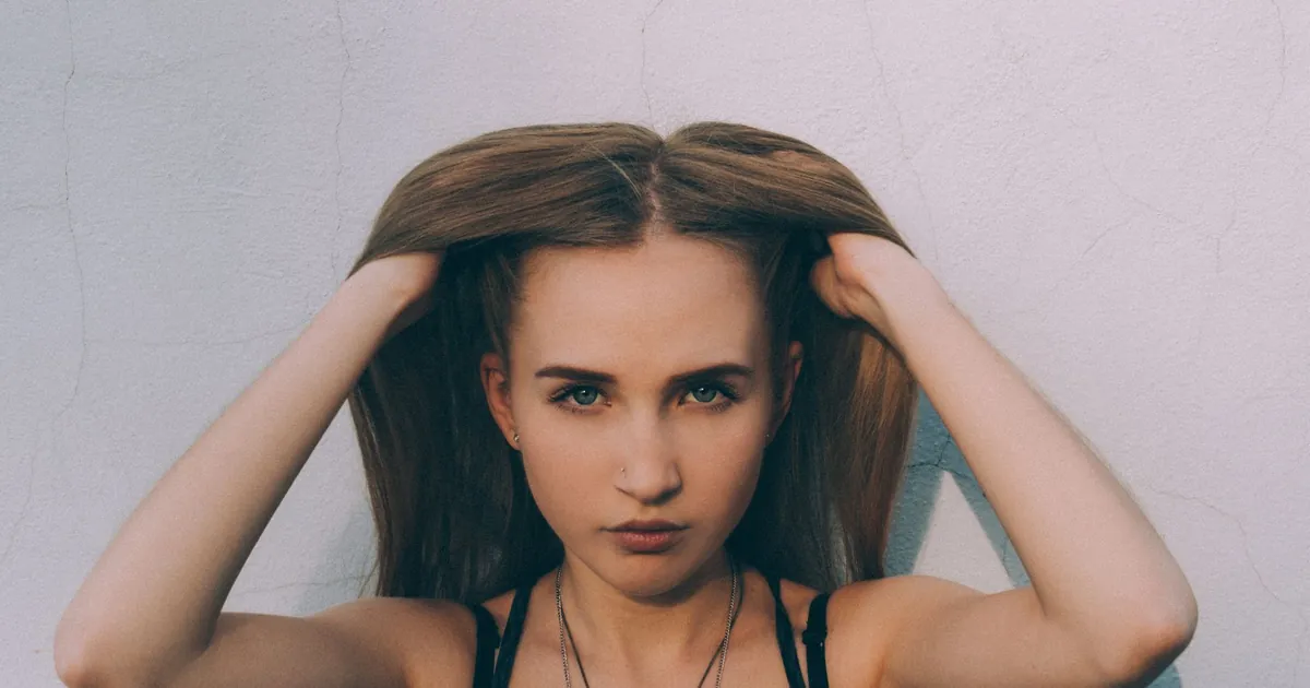 Jeune femme aux longs cheveux bruns regardant l'objectif sur fond blanc