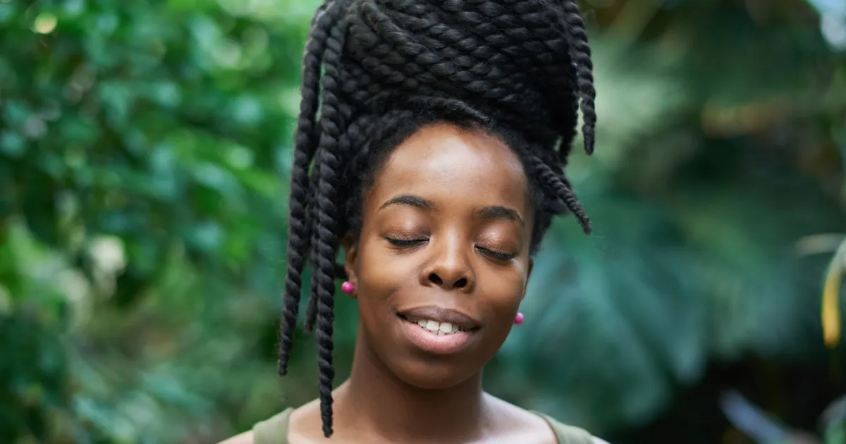 Portrait en extérieur d'une femme aux cheveux tressés, dans la nature.