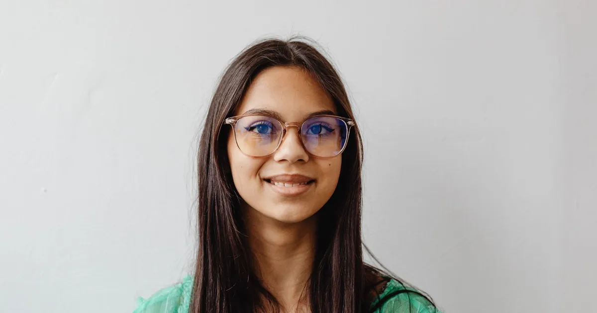 Femme souriante aux longs cheveux et lunettes, chemise verte