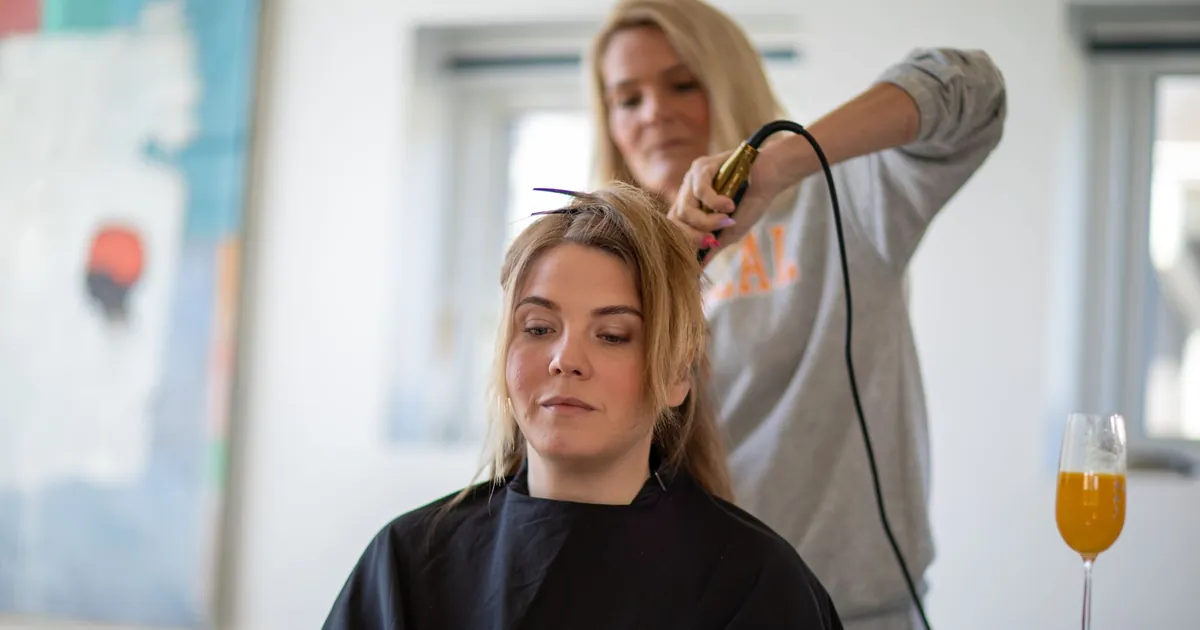 Femme faisant coiffer ses cheveux au fer dans un salon contemporain