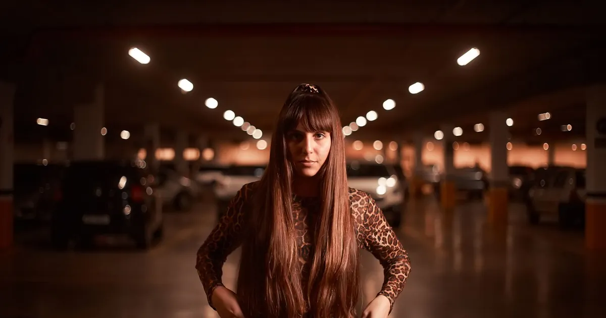 Femme élégante aux longs cheveux posant dans un parking sombre