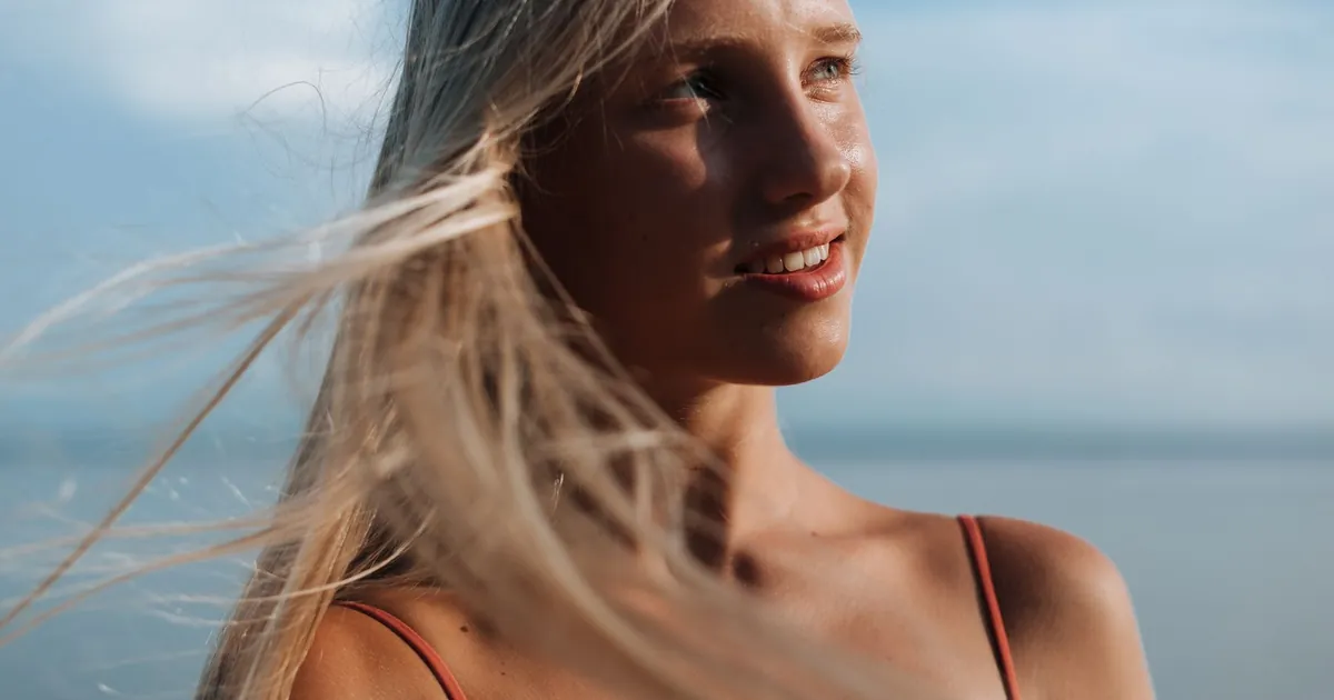 Portrait ensoleillé d'une femme aux longs cheveux blonds au bord de la mer.