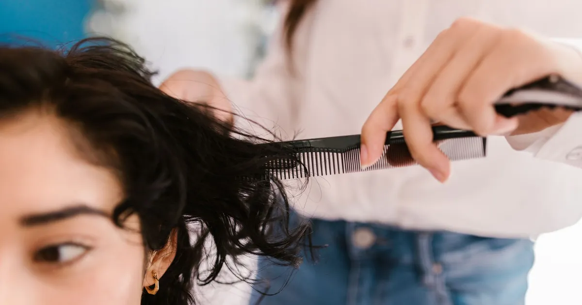 Gros plan sur une coiffeuse coupant les cheveux d'une cliente en salon.