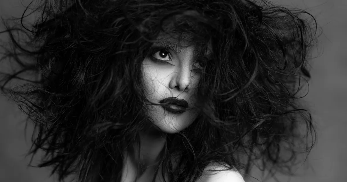 Portrait noir et blanc d'une femme aux cheveux fous et au regard intense.