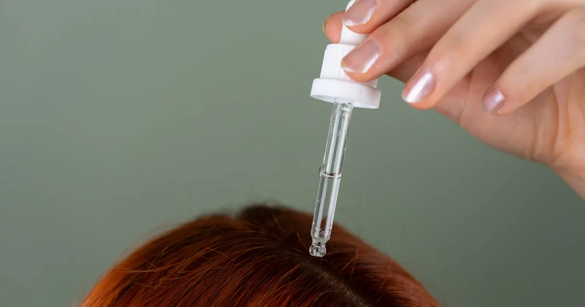 Application de sérum sur racines avec pipette sur cheveux roux