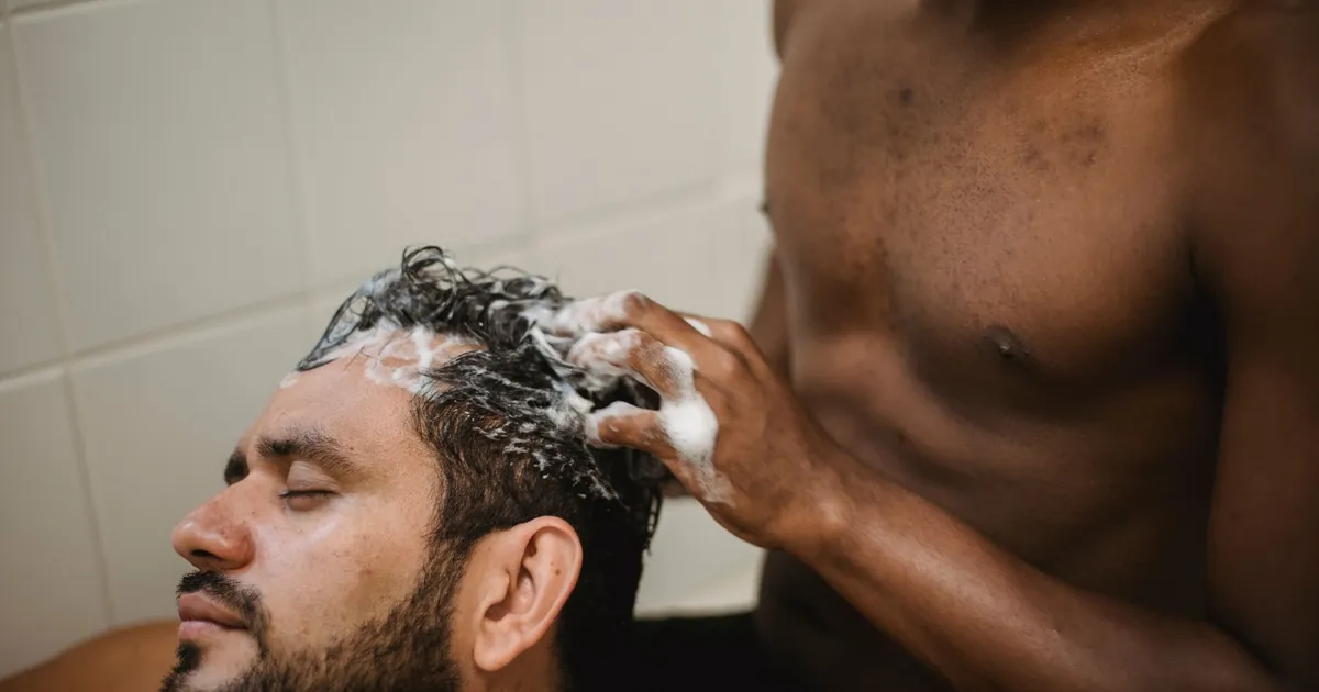Un couple se lave les cheveux avec douceur dans une salle de bain.