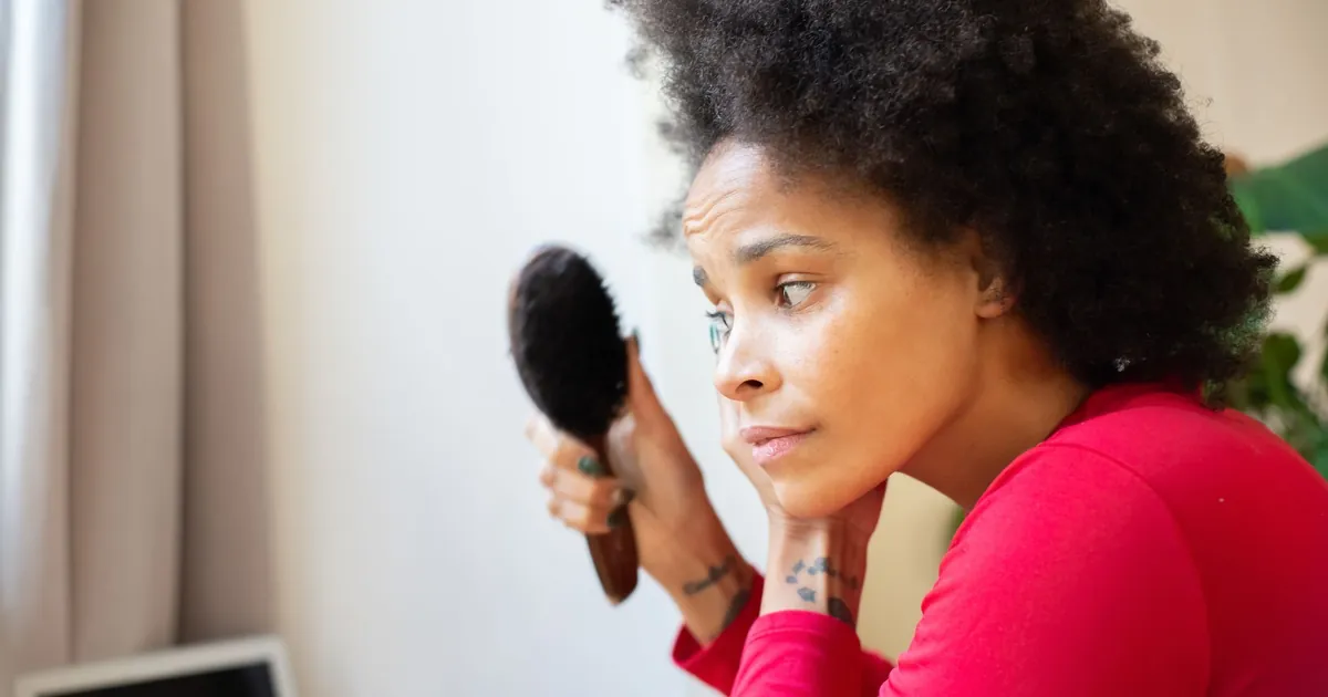 Femme aux cheveux afro se brossant les cheveux en intérieur, moment personnel.