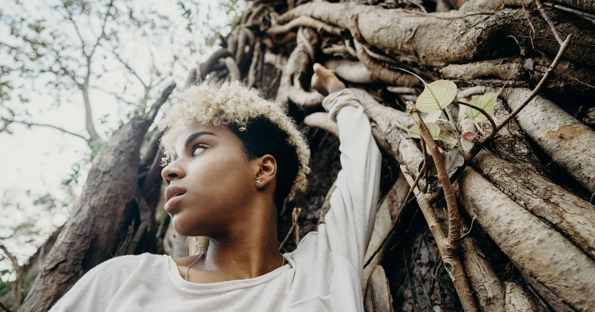 Jeune femme bouclée dans un environnement naturel, regard pensif